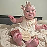 baby, infant, smiling, sitting, headband, dress, milestone_sign, six_months, blanket, bed, foot, hand, cute, indoors, child, person, skin, happy, portrait, clothing