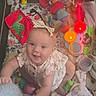 baby, baby_clothing, blanket, camera_facing, child, colorful, floral_pattern, happy, indoors, infant, nursery, play_area, playmat, plush_toy, portrait, rattles, sitting, smiling, stacking_cups, toys