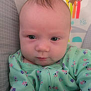 Scarlet is registered to the contest to win money with this photo: baby, infant, child, onesie, floral_pattern, face, eyes, hair, baby_chair, rainbow, sun, monkey, toy, colorful, cute, portrait, indoor, expression, closeup, person