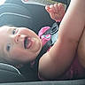 adult_arm, baby, car_interior, car_seat, child, close_up, eyes, face, hand, happy, indoor, infant, laughing, photography, pink_clothing, portrait, safety_harness, seated, smiling, vehicle