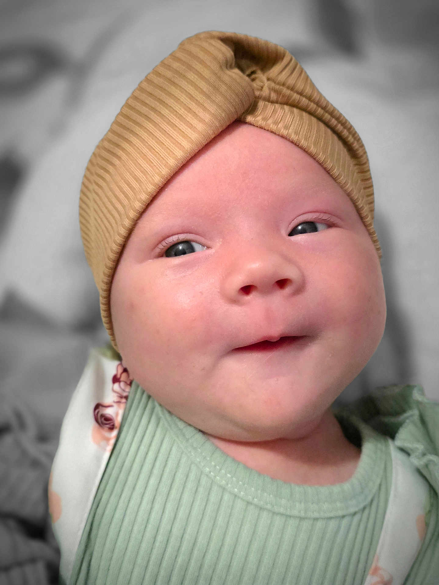 Scarlet is registered to the contest to win money with this photo: baby, infant, face, headband, clothing, green, beige, portrait, closeup, skin, expression, cute, young, child, person, apparel, soft, headwear, smile, indoors