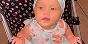Ella Mae Graham is registered to the contest to win money with this photo: baby, child, stroller, headband, dress, polka_dots, indoor, tiled_floor, table, curious, cute, infant, seated, person, hand, pink, blue, fabric, baby_clothing, portrait