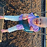 child, toddler, swing, playground, barefoot, smiling, purple_clothing, sunlight, outdoor, woodchips, play_equipment, happy, daylight, fun, recreation, playtime, person, baby, seat, park