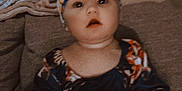 Ella is registered to the contest to win money with this photo: baby, blue, child, clothing, colorful, couch, cute, expression, face, flower, hands, headband, indoors, infant, pacifier, person, sitting, skin, toy, young