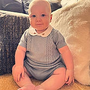 Oscar is registered to the contest to win money with this photo: baby, bodypart, clothing, couch, cushion, face, finger, furniture, hand, happy, head, homedecor, knitwear, person, photography, portrait, sitting, sleeve, smile, t_shirt