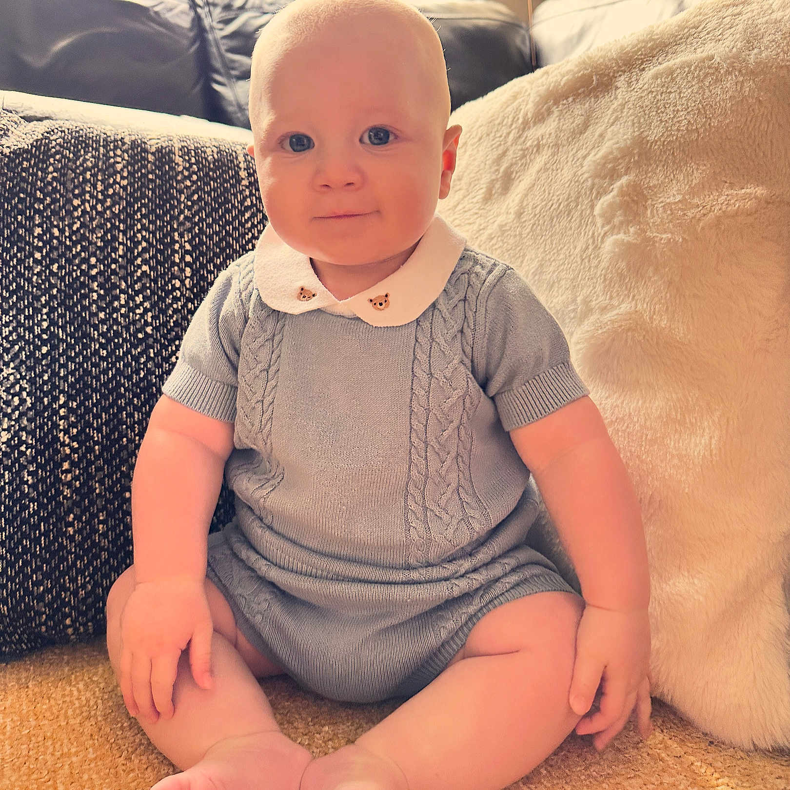 Oscar is registered to the contest to win money with this photo: baby, bodypart, clothing, couch, cushion, face, finger, furniture, hand, happy, head, homedecor, knitwear, person, photography, portrait, sitting, sleeve, smile, t_shirt