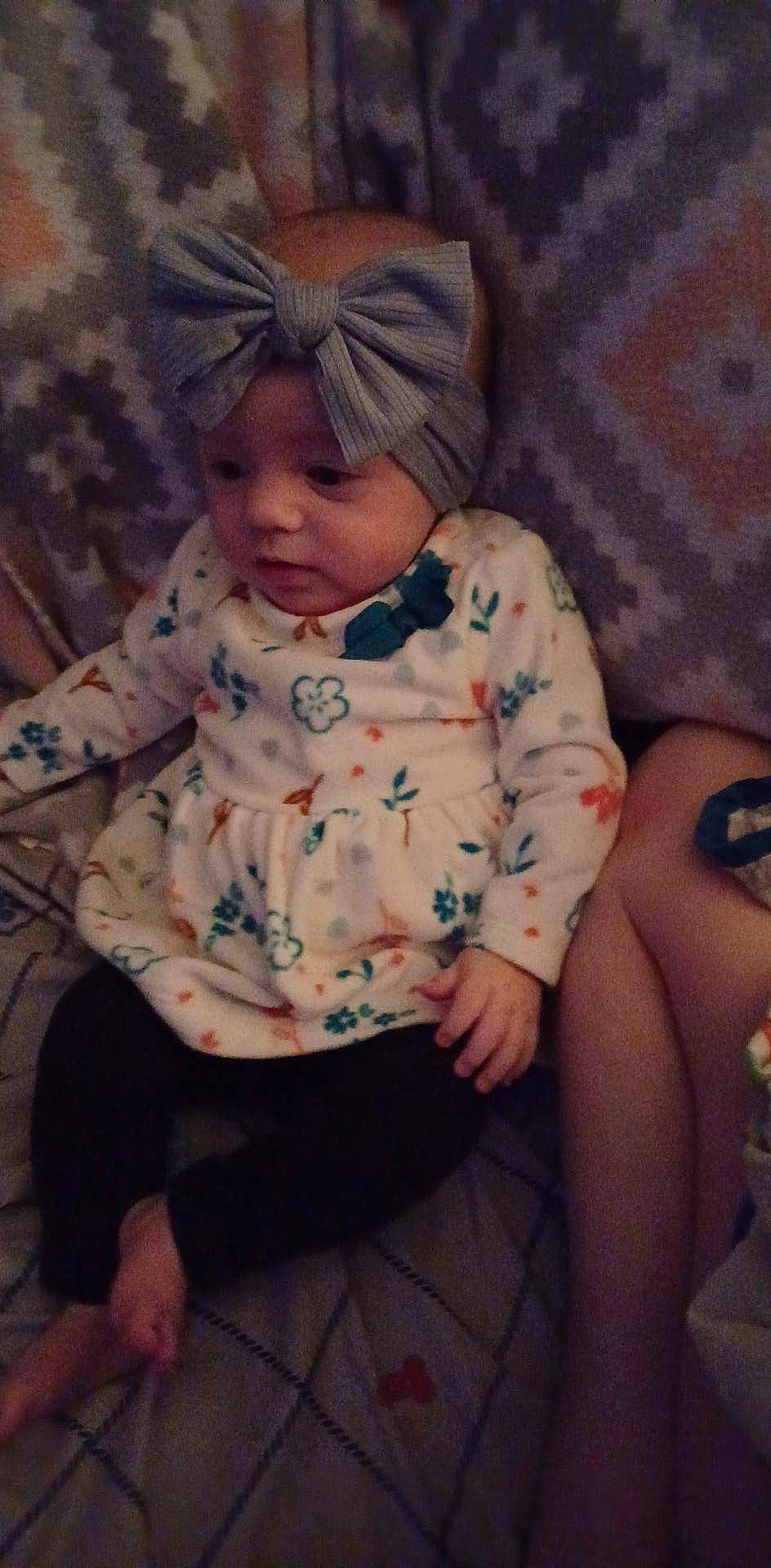 Willow is registered to the contest to win money with this photo: abdomen, baby, baby_toddler_clothing, cheek, child, comfort, eye, flesh, fun, headwear, human_leg, linens, pattern, person, portrait_photography, room, sitting, skin, sleeve, thigh