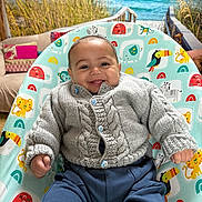 Flynn joined the competition — help win amazing prizes! baby, smiling, knitted_sweater, blue_pants, baby_seat, animal_pattern, indoor, couch, pillows, beach_mural, ocean, grass, happy, child, portrait, cozy, cute, infant, seat, playful