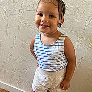 Bryhana participe au concours pour gagner de l'argent avec cette photo : toddler, child, smiling, braided_hair, beads, striped_tank_top, knitted_shorts, standing, indoor, textured_wall, happy, cute, person, portrait, young_child, floor, skin, arm, face, fashion
