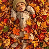 Halo is registered to the contest to win money with this photo: baby, infant, child, portrait, autumn, leaves, maple_leaves, outdoor, nature, grass, cozy, hat, beanie, brown_clothing, onesie, lying_down, sleeping, face, cute, seasonal