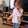 Kena a rejoint le concours — aidez-le/la à gagner de superbes lots ! child, girl, glasses, toy, bird, living_room, tv, bookshelf, books, buddha_statue, cup, speaker, carpet, sweater, pants, smile, happy, indoors, person, furniture