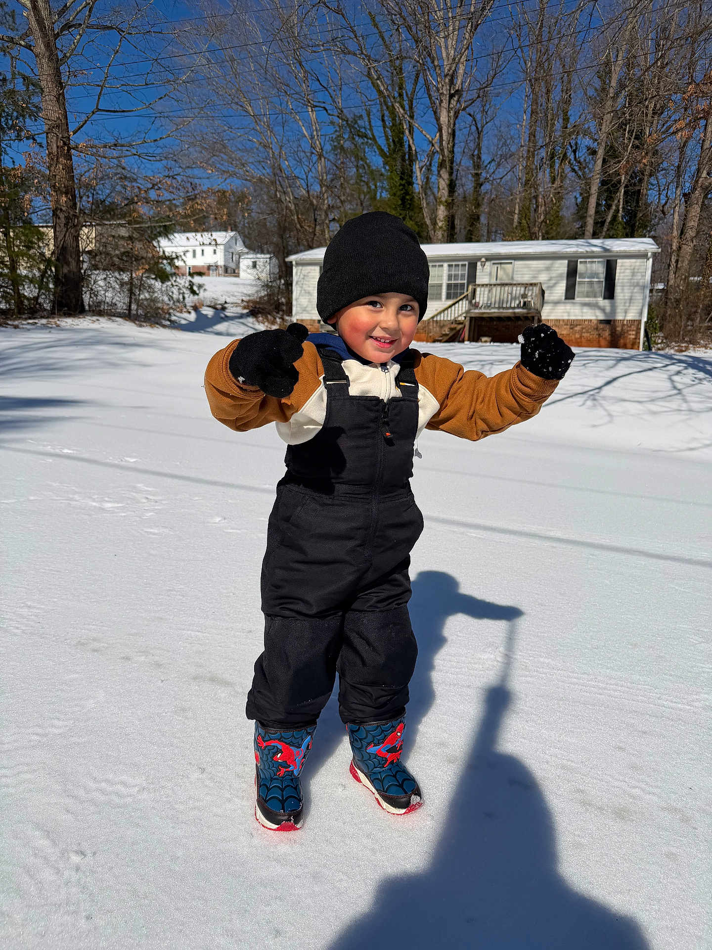 Iker joined the competition — help win amazing prizes! child, snow, winter, playful, gloves, boots, hat, outdoor, sunny, shadow, house, trees, cold, snowy_ground, smile, warm_clothing, young, person, fun, daytime