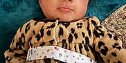 Gia is registered to the contest to win money with this photo: baby, infant, face, eyes, leopard_print, clothing, blanket, fabric, pattern, pout, cute, portrait, young_child, indoors, soft_texture, head, person, lying_down, colorful, warm_clothing
