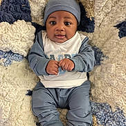 Zachariah joined the competition — help win amazing prizes! baby, beanie, bedding, blanket, blue_outfit, child, cozy, cute, eyes, hands_clenched, hat, indoor, infant, knit_blanket, onesie, portrait, seated, smile, socks, soft_texture