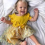 baby, barefoot, blanket, bow, child, cute, daisy_pattern, face, foot, hair, hand, happy, indoor, light, portrait, skin, smiling, soft_texture, toddler, yellow_dress