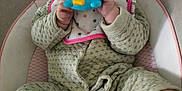 Inaya participe au concours pour gagner de l'argent avec cette photo : baby, infant, toy, chewing, green_outfit, bib, baby_seat, cushion, smiling, happy, cute, barefoot, indoor, floor, carpet, child, person, playful, closeup, portrait