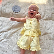Leni-Rose is registered to the contest to win money with this photo: baby, infant, smiling, yellow_outfit, blanket, patterned_blanket, lying_down, happy, cute, child, human, person, indoor, soft_texture, five_months, clothing, footwear_absent, arm_outstretched, head, portrait