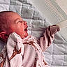 baby, newborn, infant, onesie, giraffe_pattern, sleepwear, quilted_blanket, happy, smiling, face, head, ear, hand, fingers, lying_down, indoor, soft_lighting, close_up, cute, child