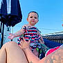 baby, beachwear, chair, clothing, face, furniture, happy, head, people, person, photography, portrait, shorts, sitting, skin, smile, summer, swimwear, t_shirt, tattoo