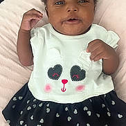 Jazaria is registered to the contest to win money with this photo: baby, infant, child, cute, panda_face, white_top, black_skirt, hearts_pattern, pink_blanket, soft_texture, lying_down, curious_expression, raised_fists, indoors, portrait, smiling, adorable, clothing, person, face