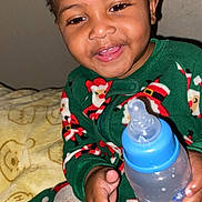 Jamarie Carr joined the competition — help win amazing prizes! toddler, child, smiling, baby_bottle, pajamas, santa_claus_pattern, indoor, blanket, bedroom, happy, cute, portrait, young_child, holiday_theme, cozy, person, infant, hand, face, clothing