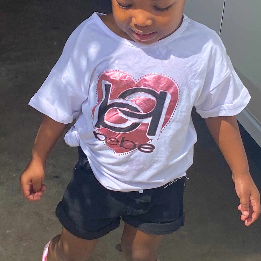 Jarhylee is registered to the contest to win money with this photo: black_shorts, braided_hair, casual_clothing, child, concrete_floor, cute, daylight, fashion, footwear, heart_design, outdoor, person, pink_sneakers, portrait, shadow, standing, sunlight, walking, white_shirt, young_child