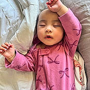 Zoey is registered to the contest to win money with this photo: baby, sleeping, onesie, pink_clothing, bed, bedding, pillow, blanket, child, peaceful, indoors, soft_texture, face, hand, relaxation, cozy, nap, infant, cute, resting