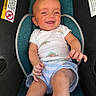 baby, car_seat, child, clothing, comfort, cute, dinosaur_print, happy, indoor, infant, leisure, onesie, person, portrait, safety_warning, seat, seatbelt, shorts, smiling, young_child