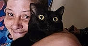 Midnight joined the competition — help win amazing prizes! person, cat, black_cat, indoor, hug, affection, wide_eyes, human_face, pet, animal, smile, close_up, arm, hair, expression, feline, domestic, companionship, shoulder, background