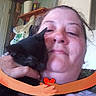Midnight is registered to the contest to win money with this photo: person, cat, black_cat, face, cuddle, indoor, close_up, hand, shelf, bag, door, cartoon_graphic, heart, affection, pet, animal, hug, portrait, casual, warmth