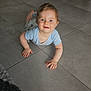 baby, child, crawling, blue_shirt, tiled_floor, rug, living_room, plant, furniture, smiling, happy, indoor, face, person, cute, young_child, floor, home, modern, curly_hair