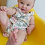 baby, bright, chair, child, cute, expression, face, floral_pattern, foot, hand, indoors, infant, playful, romper, sitting, skin, smiling, wooden_floor, yellow_chair, young_child