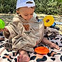 Soan a rejoint le concours — aidez-le/la à gagner de superbes lots ! toddler, child, beach, blanket, towel, cap, toy, yellow_toy, orange_toy, plastic_toy, sand, outdoor, sunlight, shadow, nature, greenery, cute, barefoot, sitting, portrait