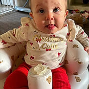 Hollie is registered to the contest to win money with this photo: baby, bear_pattern, carpet, child, clothing, cute, face, festive, holiday, indoor, infant, inflatable_chair, person, portrait, red_pants, sitting, smile, sweater, tongue_out, toy