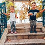 child, children, boy, girl, steps, stairs, gazebo, park, autumn, leaves, railing, metal_railings, striped_pants, crocs, sneakers, smile, outdoors, portrait, two_children, playful