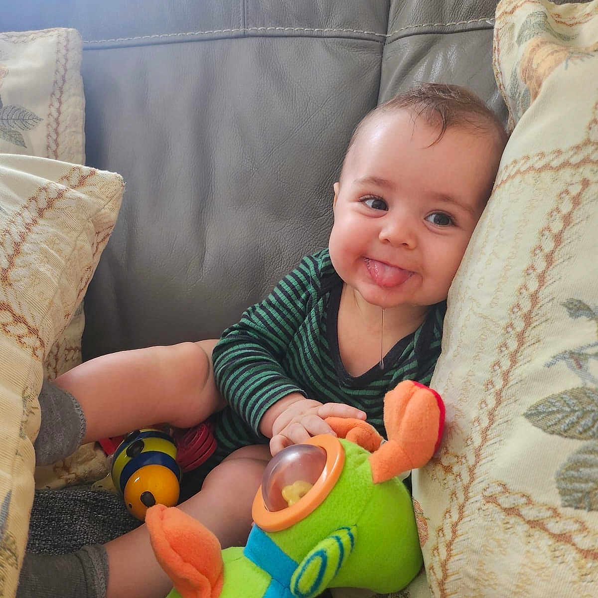 Elio participe au concours pour gagner de l'argent avec cette photo : baby, child, cozy, cushion, cute, face, fun, happy, home, indoor, infant, person, playful, plush_toy, sitting, smiling, sofa, soft_toys, striped_clothing, tongue_out