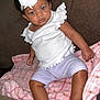 baby, child, curly_hair, blue_eyes, white_bow, headband, white_top, lilac_shorts, pink_blanket, plaid_blanket, couch, brown_couch, indoor, person, infant, cute, sitting, looking, soft_texture, relaxed