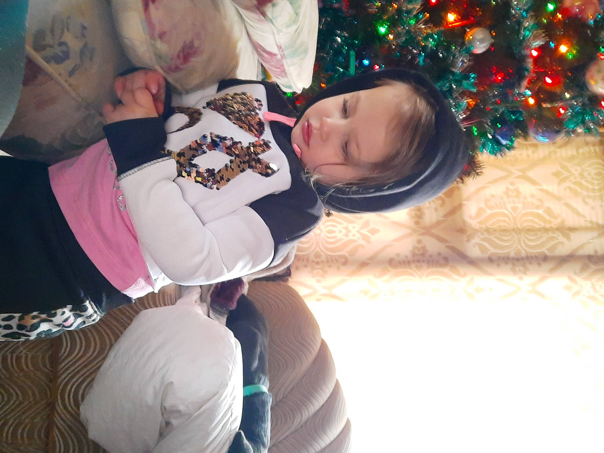 Haven is registered to the contest to win money with this photo: baby, child, christmas_decoration, christmas_ornament, christmas_tree, comfort, conifer, event, fun, happy, holiday, human_leg, knee, lap, leg, leisure, person, sitting, thigh, toddler