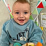 baby, smiling, blue_eyes, plush_toy, baby_seat, colorful, clothing, happy, infant, portrait, child, cute, indoors, playful, toy, sitting, face, young_child, joyful, casual