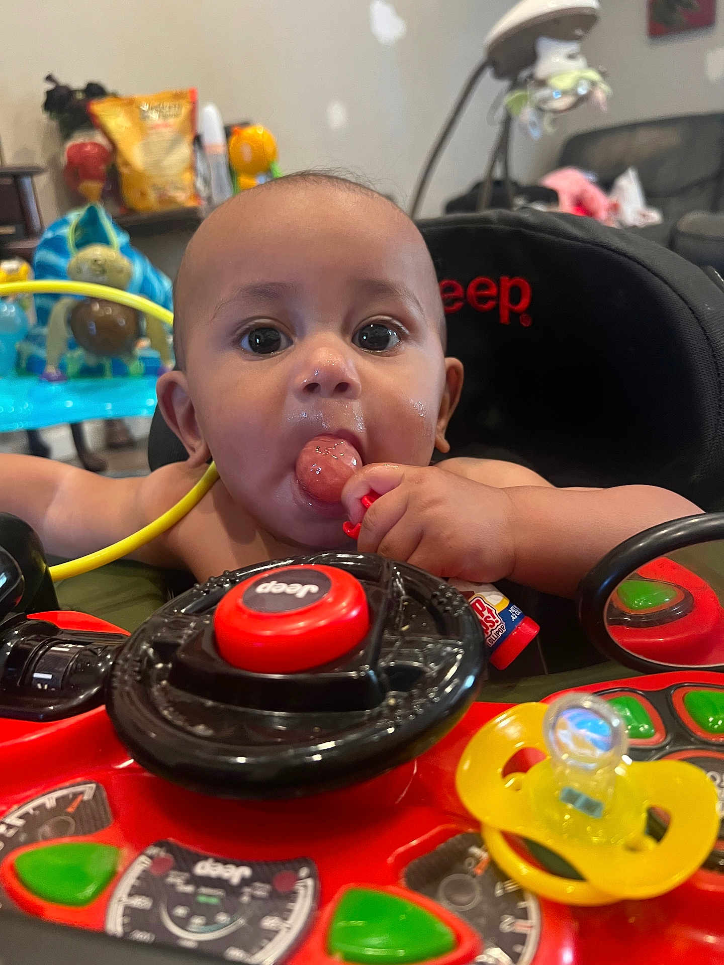 Romeo joined the competition — help win amazing prizes! baby, child, toy_car, lollipop, steering_wheel, jeep, indoor, colorful, playful, infant, face, hand, seat, mirror, pacifier, toy, home, curious, chewing, closeup