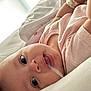 baby, infant, close_up, face, eyes, pink_clothing, soft_toys, lying_down, curious, expression, skin, mouth, head, child, indoors, blanket, cozy, resting, newborn, portrait