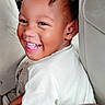 Chozen is registered to the contest to win money with this photo: child, toddler, smiling, laughing, portrait, face, teeth, braids, hair, baby, car_seat, seated, indoors, vehicle, white_shirt, happy, joyful, close_up, person, photography