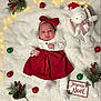 baby, red_bow, red_skirt, white_tights, plush_bunny, christmas_ornaments, pine_cone, holly, christmas_lights, festive, holiday, blanket, cute, infant, white_background, decoration, winter, toy, smiling, portrait