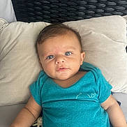 Ayan participe au concours pour gagner de l'argent avec cette photo : baby, infant, child, pillow, cushion, blue_shirt, whale_emblem, soft_texture, woven_background, indoor, portrait, cute, relaxed, cozy, small_hand, head, face, eyes, skin, clothing