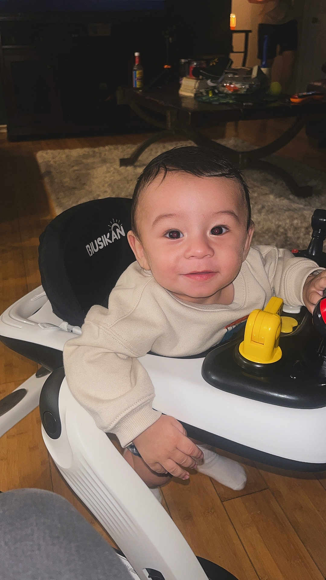 Noah joined the competition — help win amazing prizes! baby, smile, face, child, walker, toy, indoor, floor, wood, person, clothing, socks, furniture, living_room, table, happy, cute, play, young_child, seat