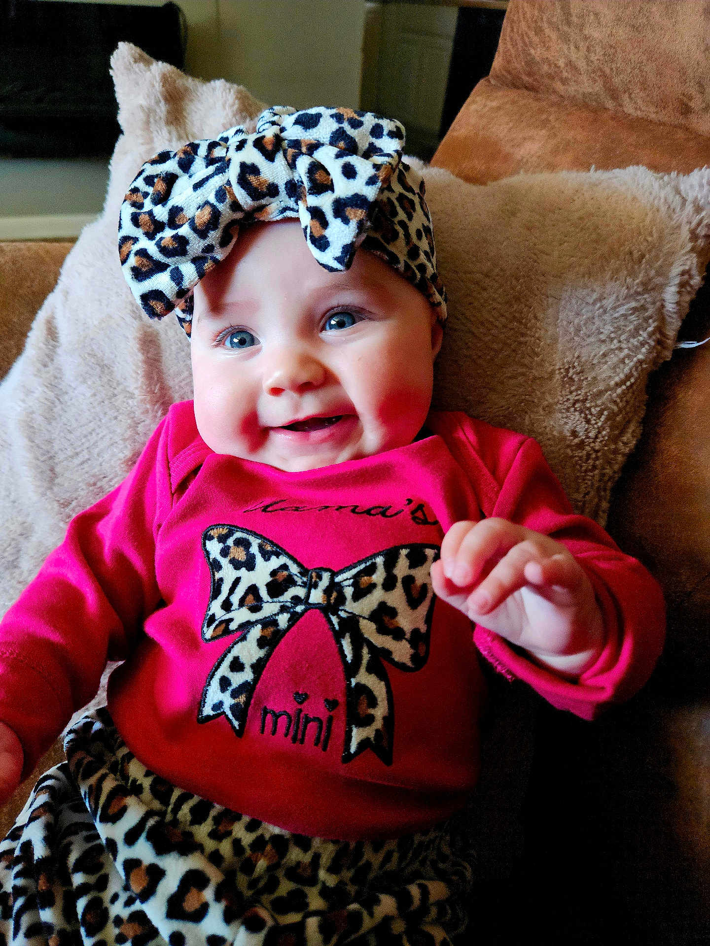 Ember joined the competition — help win amazing prizes! baby, infant, smiling, headband, leopard_print, red_clothing, couch, plush_pillow, blue_eyes, cute, happy, child, portrait, indoor, soft_texture, hand, close_up, fashion, toddler, cozy