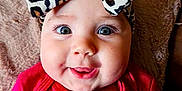 Ember joined the competition — help win amazing prizes! baby, child, infant, headband, leopard_print, pink_clothing, smile, face, cheeks, eyes, cute, portrait, indoors, blanket, soft_texture, apparel, bow, happy, person, closeup