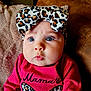 Ember is registered to the contest to win money with this photo: baby, child, face, blue_eyes, headband, leopard_print, bow, pink_clothing, chubby_cheeks, cute, portrait, indoor, soft_texture, cushion, closeup, expression, person, infant, fashion, warm