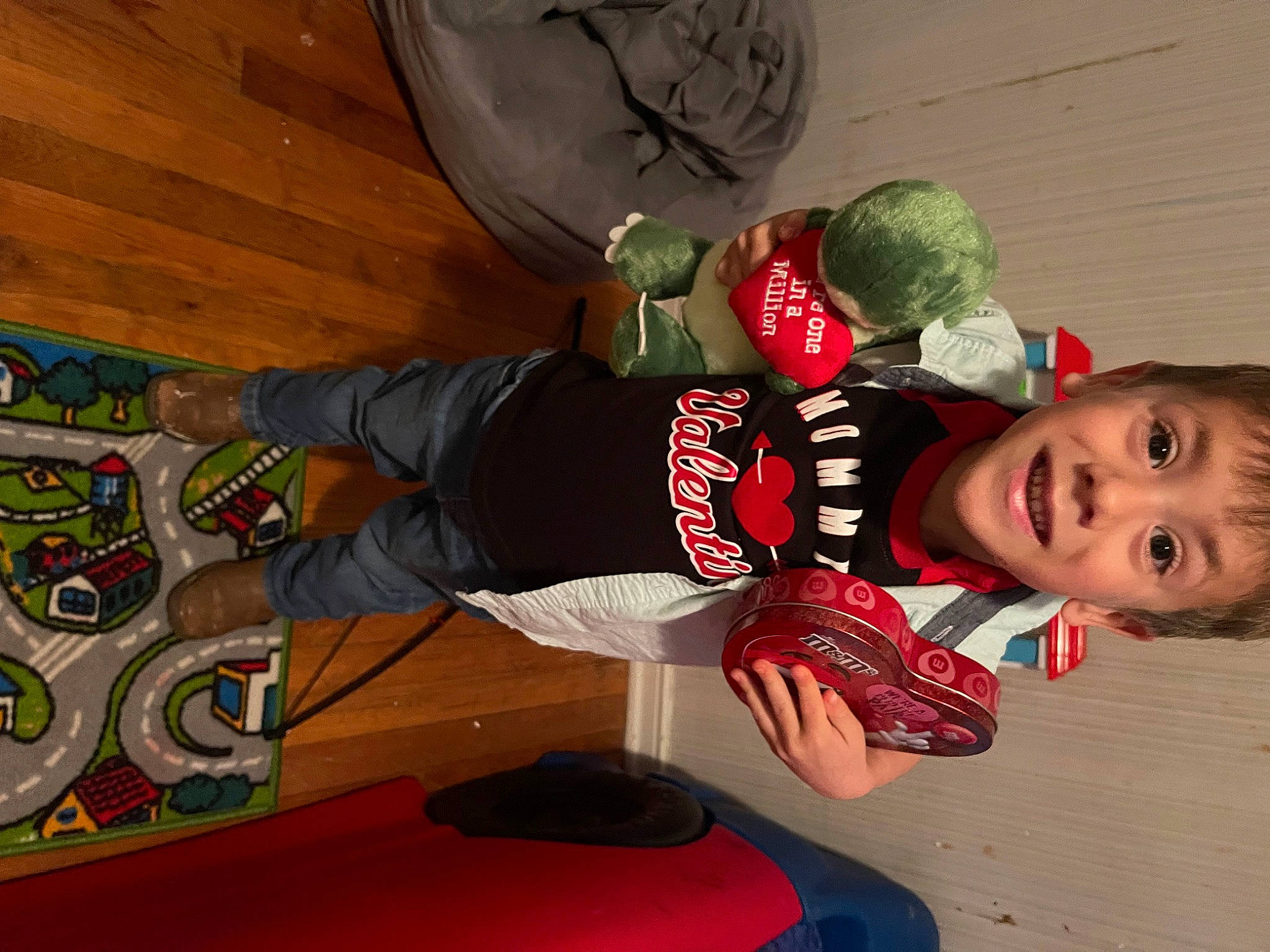 Ashton is registered to the contest to win money with this photo: carmine, child, flooring, fun, knee, leisure, outdoor_shoe, person, personal_protective_equipment, play, recreation, room, sitting, smile, sports, sportswear, t_shirt, toddler, walking_shoe, wood