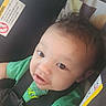 Gabriel joined the competition — help win amazing prizes! baby, child, car_seat, green_shirt, curly_hair, safety_harness, seatbelt, infant, cute, smiling, indoors, warning_label, closeup, person, young_child, portrait, seat, car, happy, face